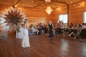 Wedding celebration in a rustic barn venue with geometric wall art and string lighting.