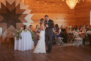 Wedding celebration dance in a rustic venue with wooden walls and hanging lights.