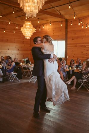 Couple sharing a dance lift in a rustic wedding venue with elegant chandeliers.