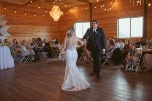 Elegant barn wedding reception with chandelier and string light decorations.
