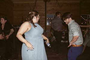 Wedding guests dancing together in a rustic venue with wood paneled walls.
