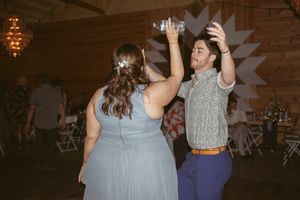 Guests enjoying a lively dance party in a rustic barn wedding venue.
