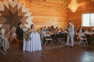 A rustic venue space with wooden walls, chandeliers, star-shaped wall decor and folding chairs set for an event.