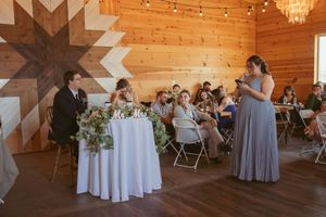 Reception celebration inside a rustic wooden venue with geometric wall art, elegant table settings and chandelier overhead.