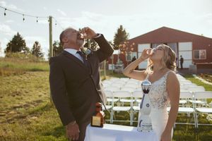 Wedding couple poses together during sunset with string lights hanging overhead outdoors.