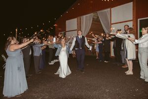Wedding party dancing and celebrating in a dimly lit outdoor reception area.