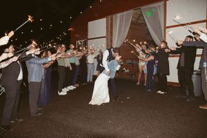 Wedding guests dancing in line formation during an evening reception under string lights.