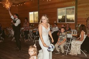 A wedding reception in a rustic wood-paneled venue with string lights and folding chairs.