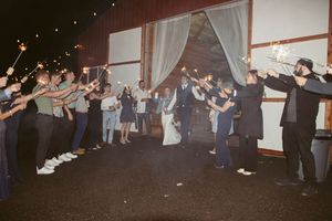 Wedding reception guests dancing in a rustic barn venue with string lights.