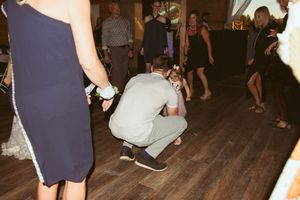 Party guests gather on a rustic dance floor during a wedding reception at a barn venue.