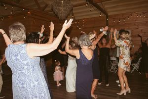 Wedding guests dancing with their hands in the air during the reception party.