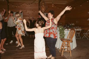 People dance and celebrate at a rustic barn wedding reception with string lights overhead and wooden decor.