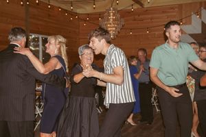 Wedding guests dance and celebrate together under string lights in rustic barn venue.