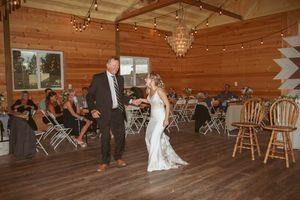 Wood-paneled reception hall decorated with elegant chandeliers and string lights.