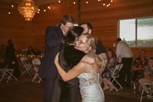 Couples slow dancing at an elegant barn venue with wooden walls and chandelier lighting.