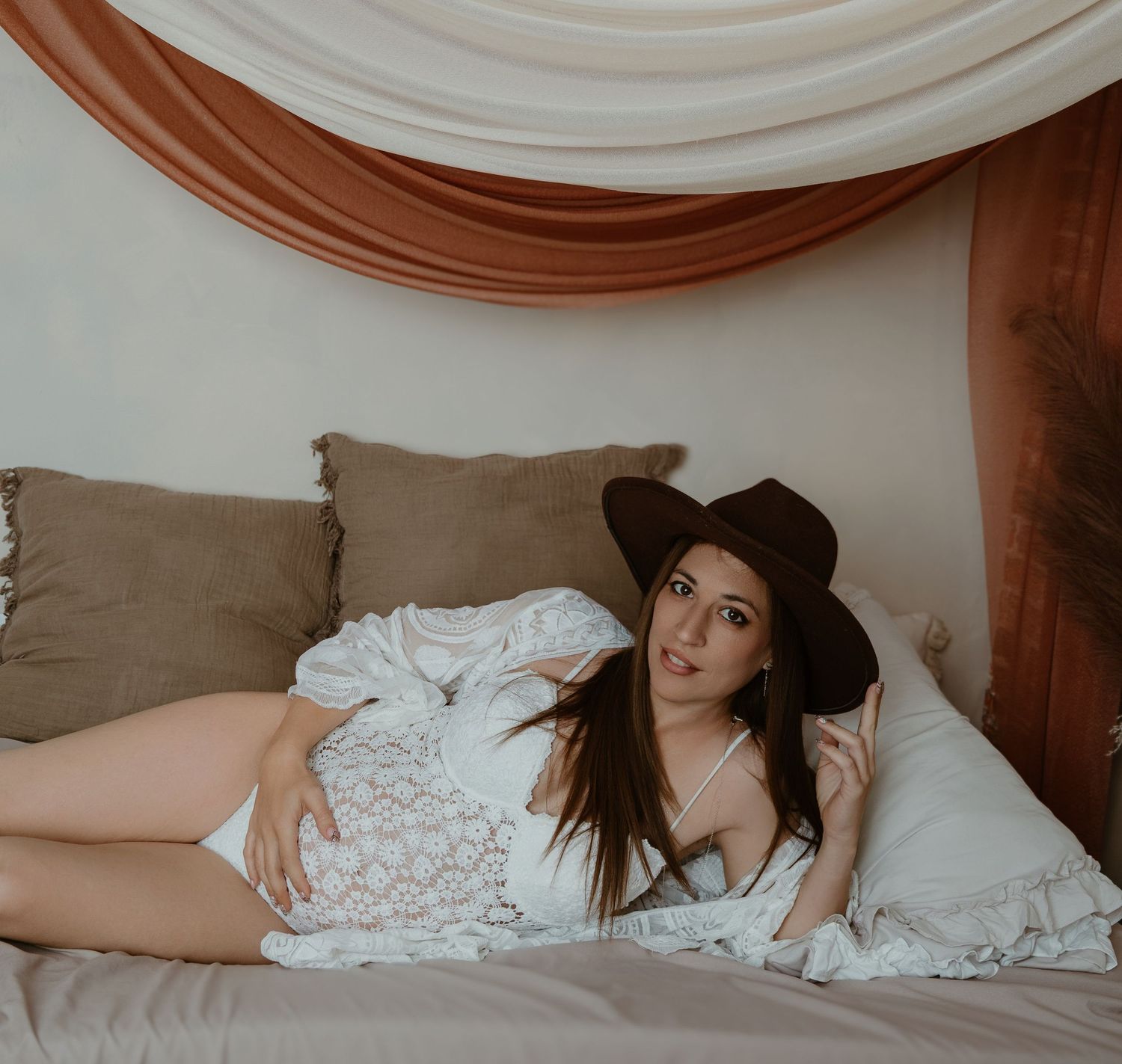 Mujer embarazada en sesión de fotos de embarazo en Valencia, con vestido boho blanco y sombrero