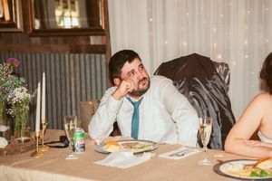 A wedding guest shows signs of fatigue while sitting at a decorated reception table.