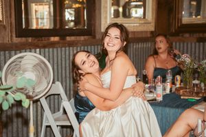 Wedding celebration with guests dancing and embracing in a rustic barn setting.