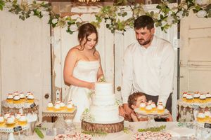 Wedding dessert table decorated with greenery garland and multiple tiers of cupcakes.