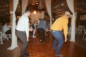 People dancing in a barn-style venue decorated with white drapes and twinkling lights.