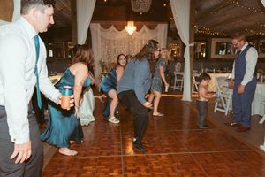 Wedding guests dancing and having fun on a wooden dance floor at a reception venue.