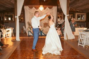 A couple dancing together on a wooden dance floor at their barn wedding reception.