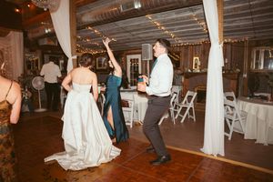 A group of people dancing together during a reception celebration on a rustic wooden dance floor.