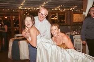 Guests enjoying a lively reception in a barn-style venue with string lights overhead.