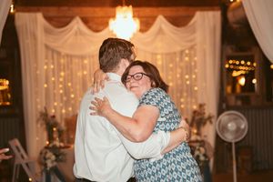 A couple shares a joyful dance moment at a wedding reception with fairy lights and white draping in the background.