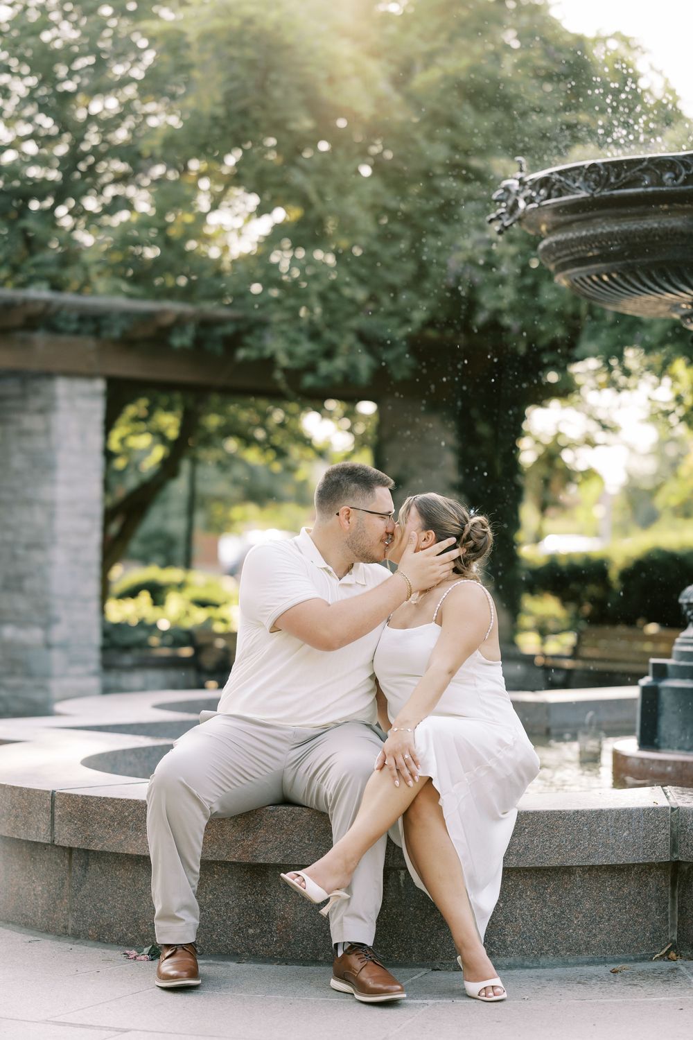 A couple in white outfits sharing romantic moments on stone steps during a golden hour photoshoot session.