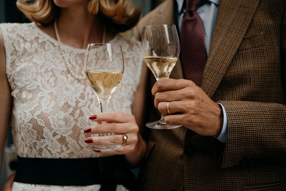 Bride and groom in elegant wedding attire clinking champagne glasses to celebrate their marriage.