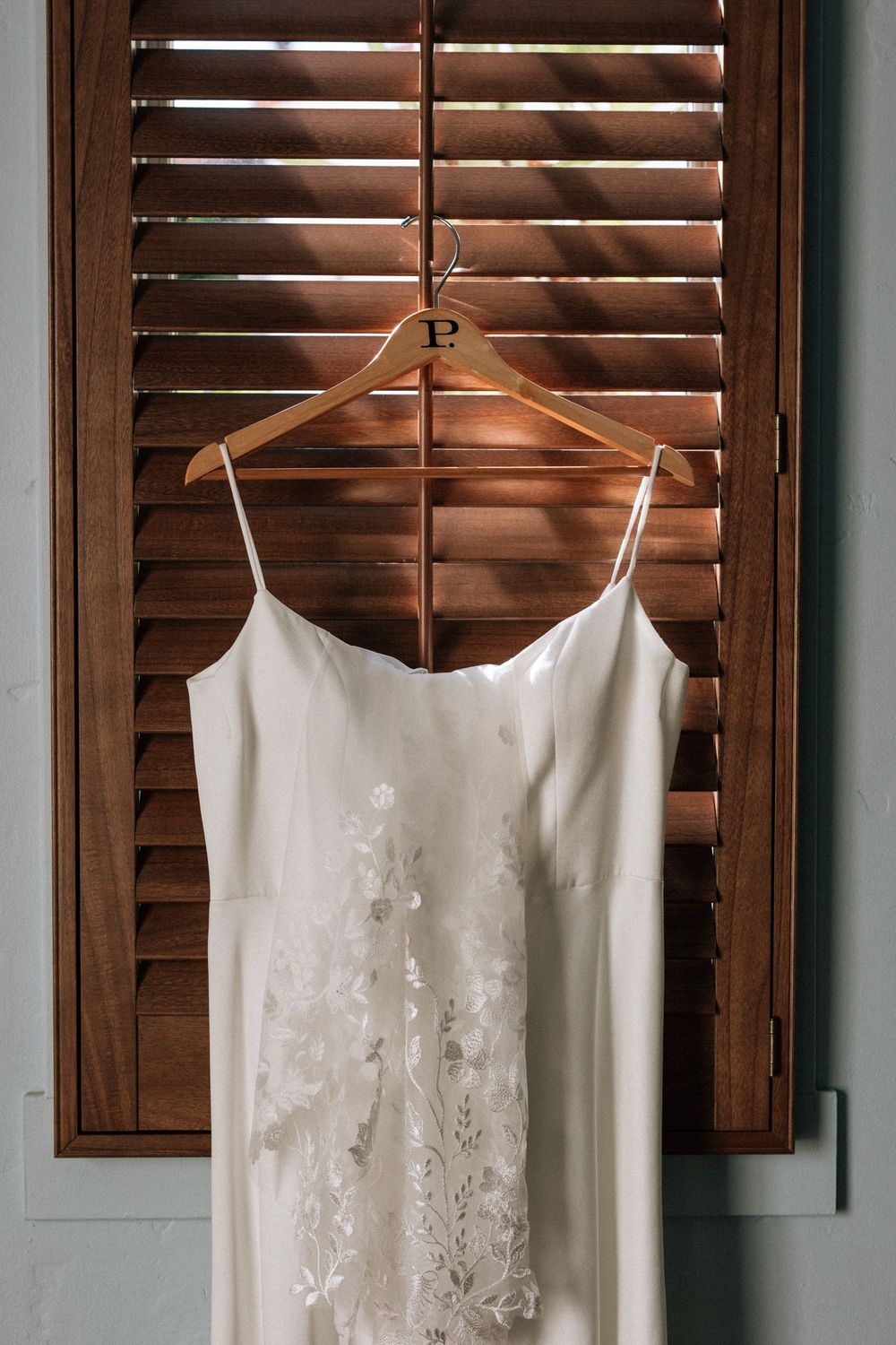 A short wedding dress hangs on a hanger