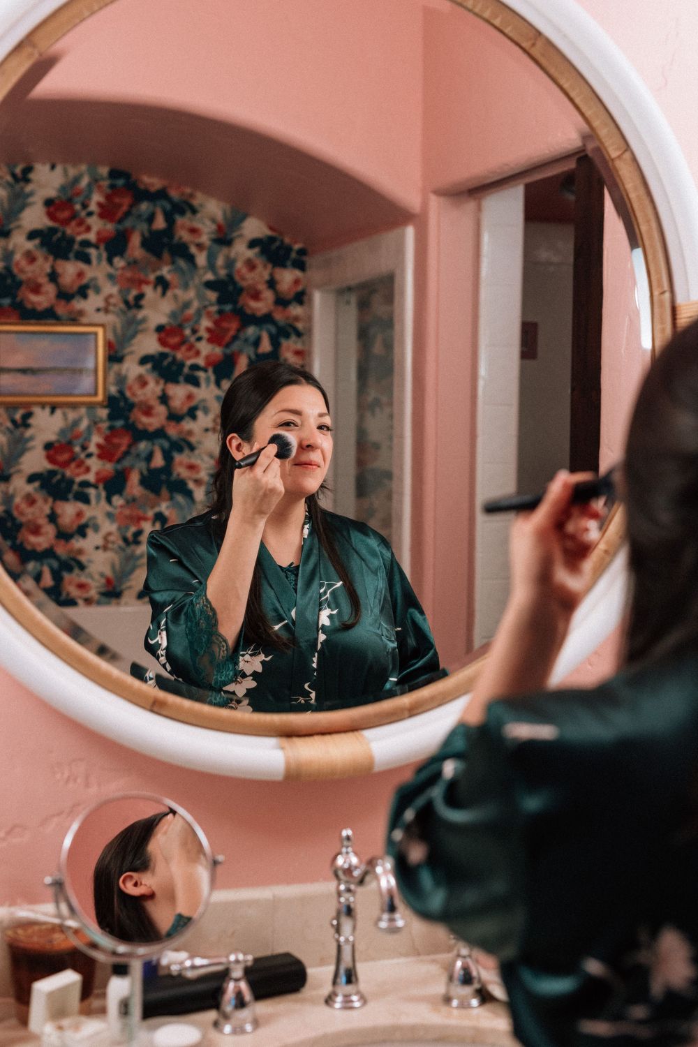 Bride applies makeup in mirror getting ready for her wedding day