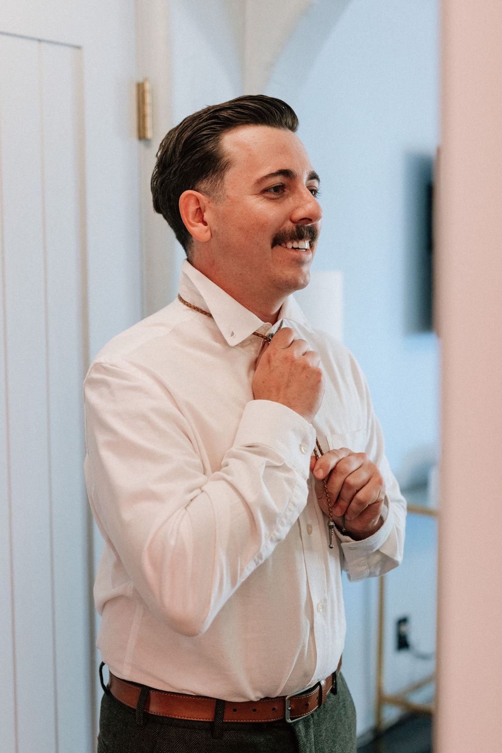 Groom fastens tie getting ready for wedding day in santa Barabra