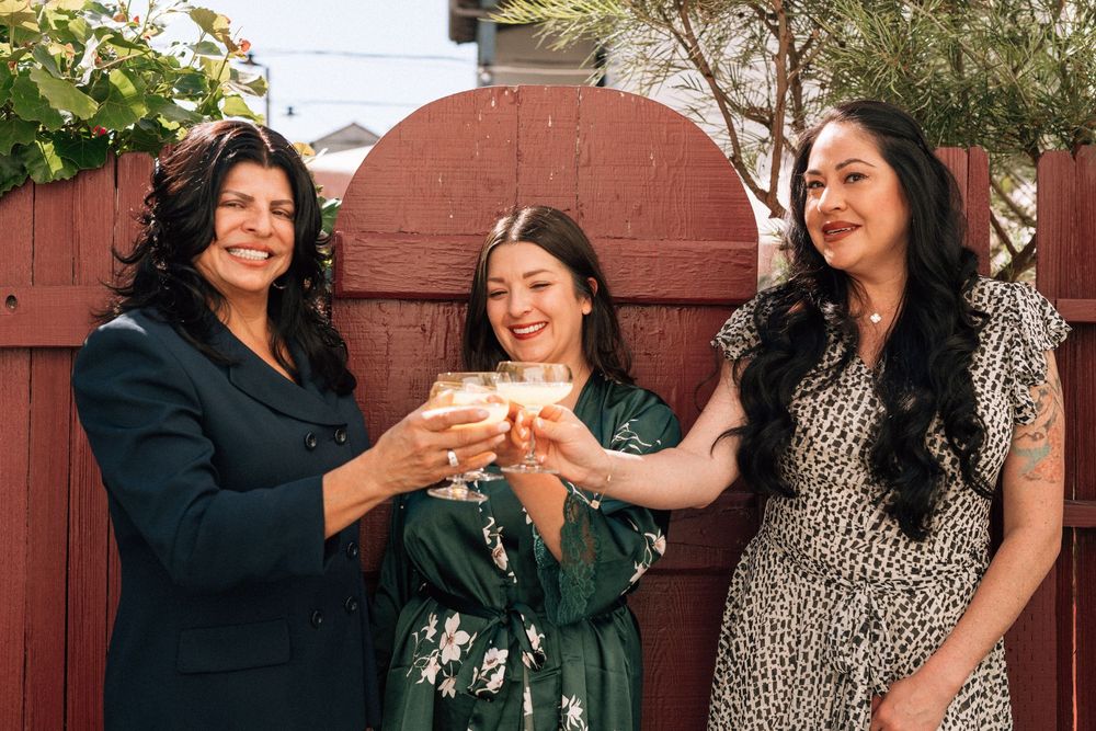 Bride, mother, and sister cheer and toast outside in santa barbara