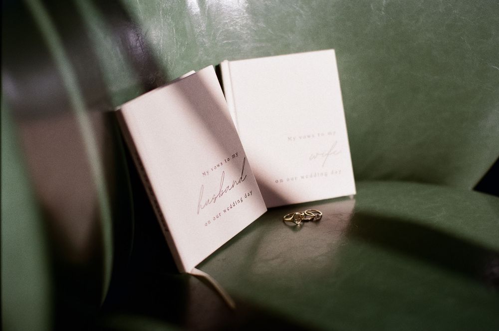 Shadows play across his and her vow books before a wedding day captured on 35mm film