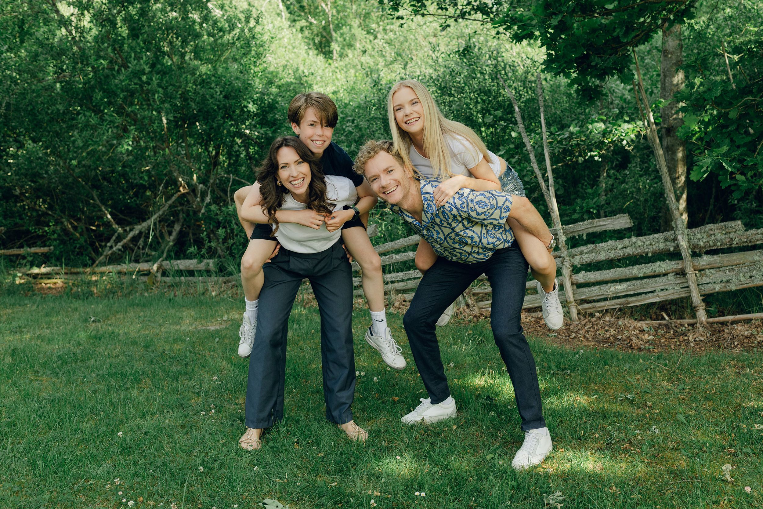 Familjefotografering med Peter, Lydia, Millie och Hayden Johansson. Fotograf Rebecca Nordin. Barnen på föräldrarnas rygg.