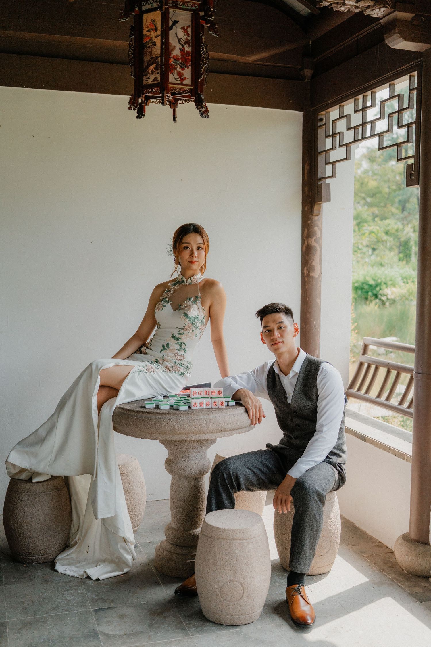 Couple sitting at stone furniture in a traditional Chinese courtyard with latticed windows.