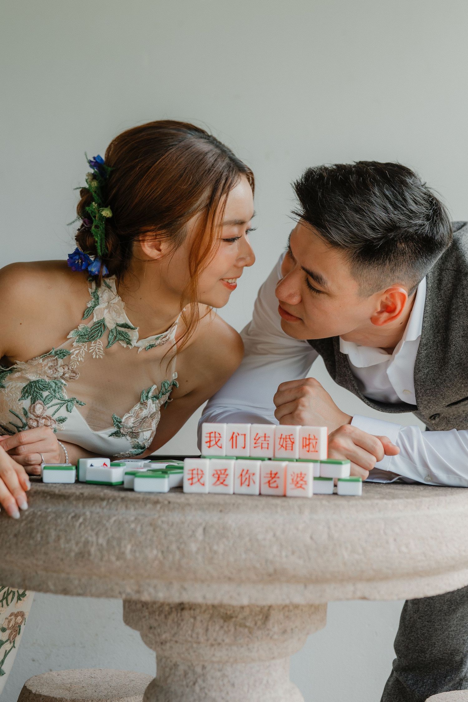 Couple lying down with Chinese mahjong tiles and romantic messages arranged in front of them.