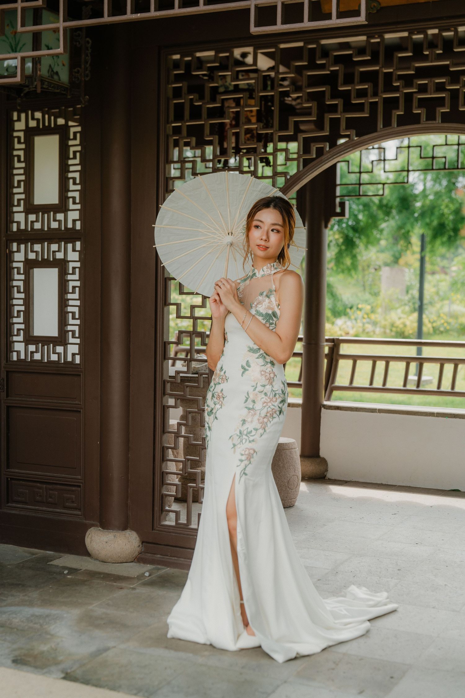 Elegant white mermaid gown with floral details is showcased in a traditional Chinese pavilion with ornate lattice screens.