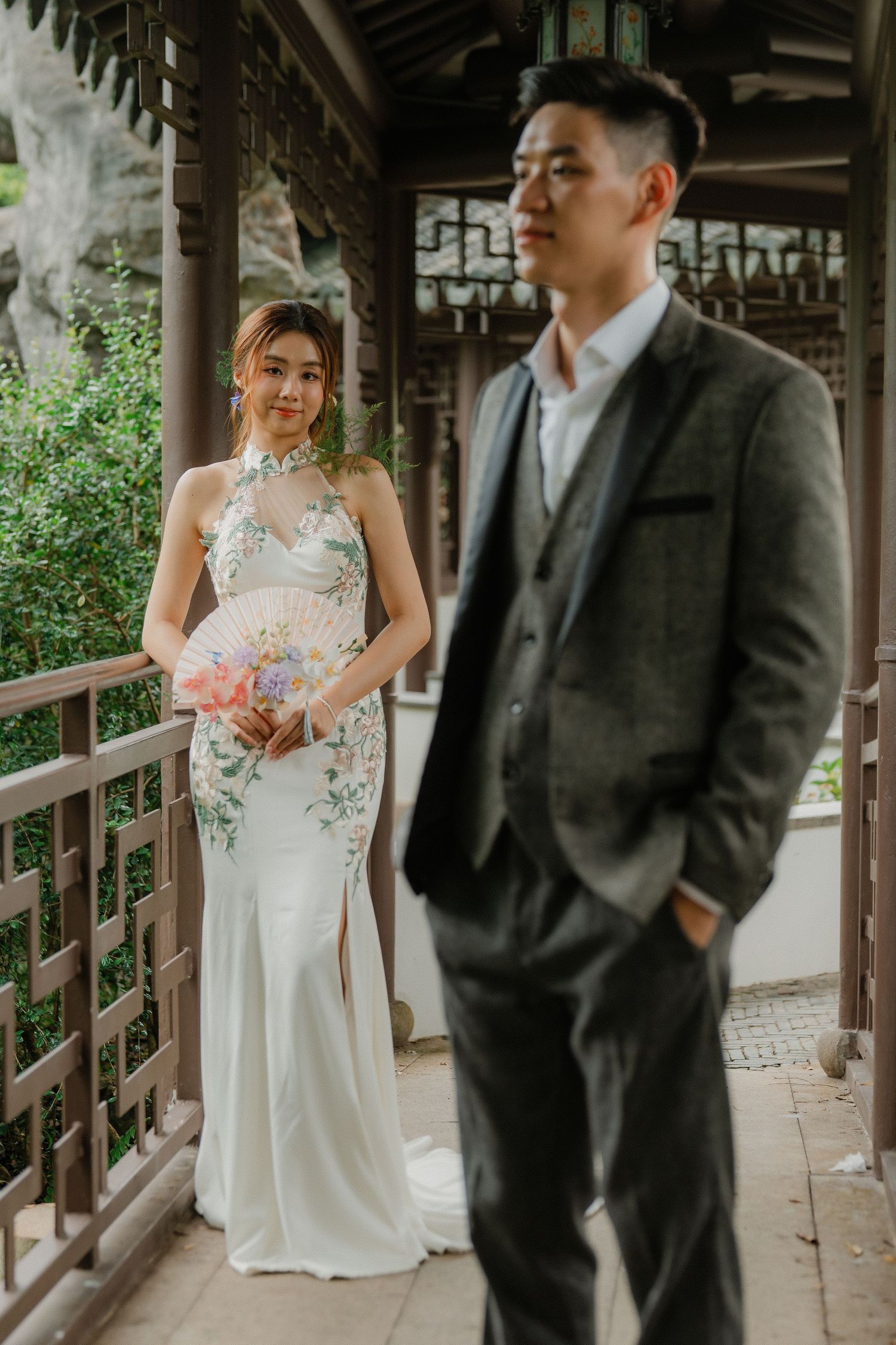 Wedding couple in white dress and dark suit share romantic moments on a wooden covered porch during their special day.