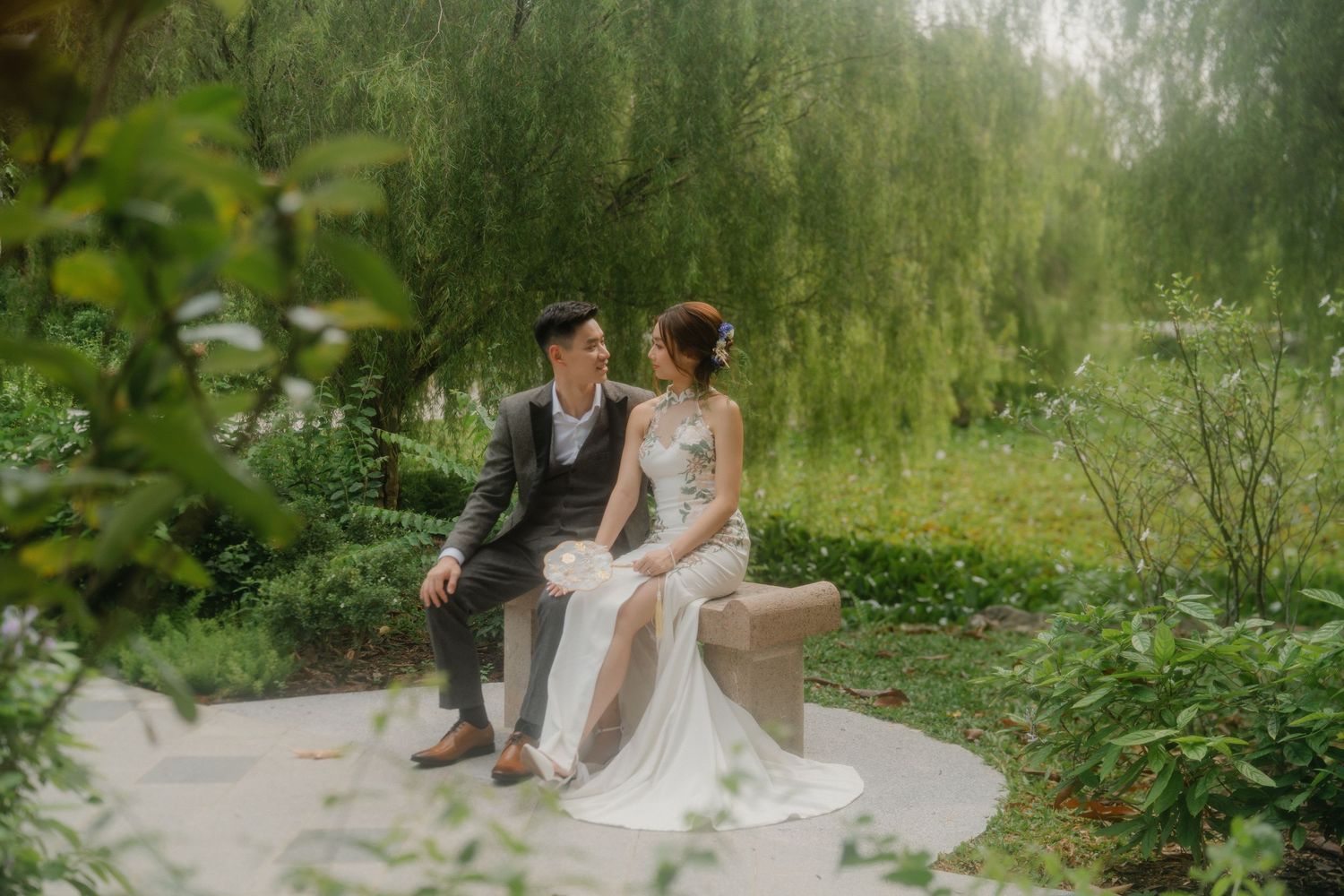 Couple sharing an intimate moment on garden steps surrounded by lush greenery.