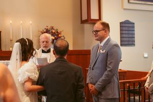 Wedding ceremony taking place in a church with wooden pews and lit candles on the altar.