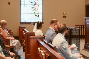 Traditional church interior with stained glass windows and wooden pews during a wedding service.