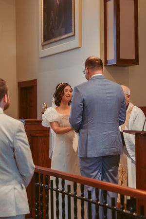 A wedding ceremony takes place inside a traditional church sanctuary with wooden furnishings.