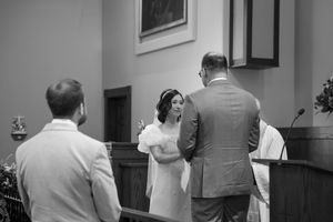 A small group stands conversing during a ceremony inside a church sanctuary.