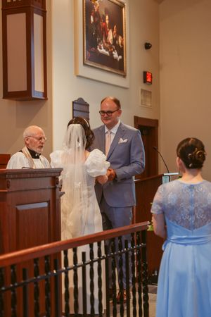 A traditional church wedding ceremony with clergy and attendants in blue and gray attire at the altar.