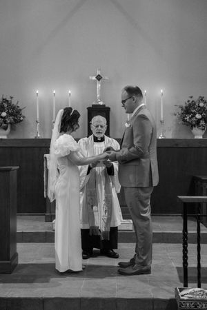 A black and white photo captures a traditional church wedding ceremony with candles and an altar.