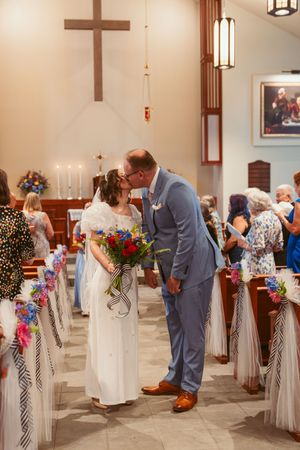 A tender moment at a church wedding ceremony with colorful floral decorations and candles at the altar.