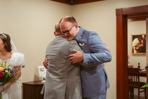 An emotional embrace shared between formally dressed individuals at a wedding celebration.